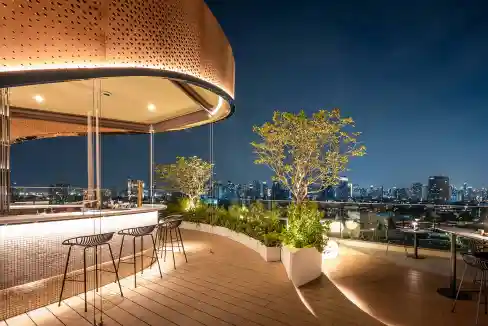 Rooftop terrace of Bangkok Sukhumvit 71 Aparthotel with city skyline view at night.