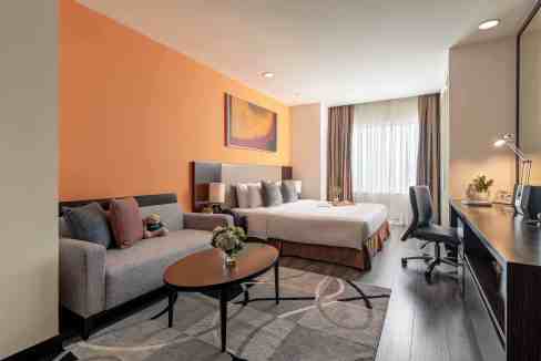 Spacious hotel room with a sofa, large bed, and work desk at Hanoi Hoa Binh Aparthotel.