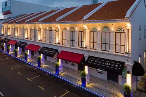 Exterior view of Penang Bahari Parade Aparthotel with illuminated facade and vibrant street lighting.