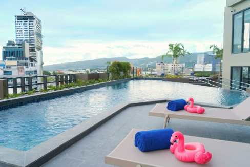 Rooftop pool area with lounge chairs and pink flamingo floaties in a modern hotel in Cebu City.