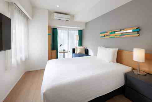 Comfortable hotel room in Tokyo Nishi Shinjuku with contemporary furnishings and bright ambiance.
