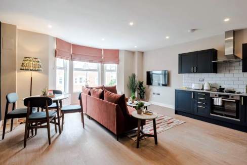 Bright living room with modern kitchen and dining area at White City Askew Apartments.
