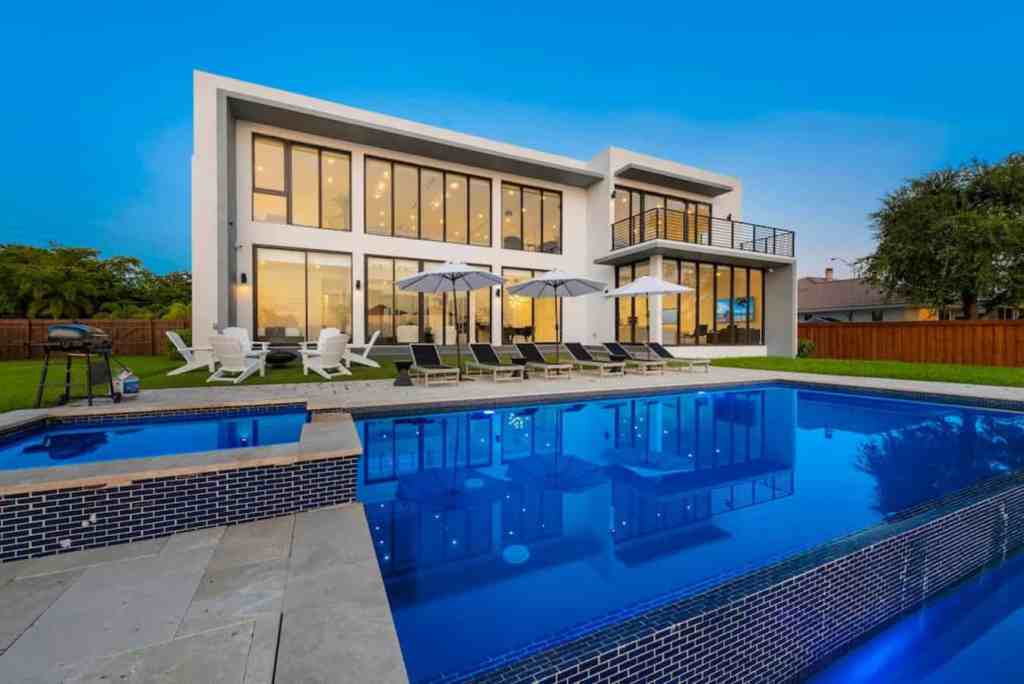 Luxury modern house with pool, outdoor lounge, and sunset view.