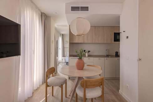 Modern minimalist kitchen and dining space with natural light and wooden furniture.