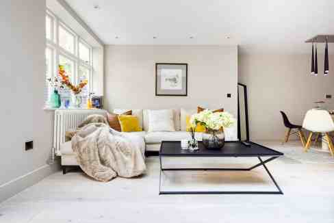 Bright living room with white walls, large windows, and stylish decor elements.