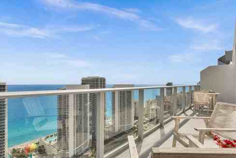 Panoramic view of city skyline and ocean from a modern balcony.