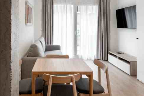 Modern living room with dining table, sofa, and large window, minimalist interior decor.