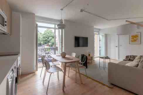 Modern living room with balcony view, natural light, and minimalist furniture design.