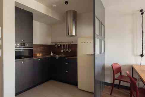 Modern kitchen with black cabinets, stainless steel appliances, and wooden backsplash.