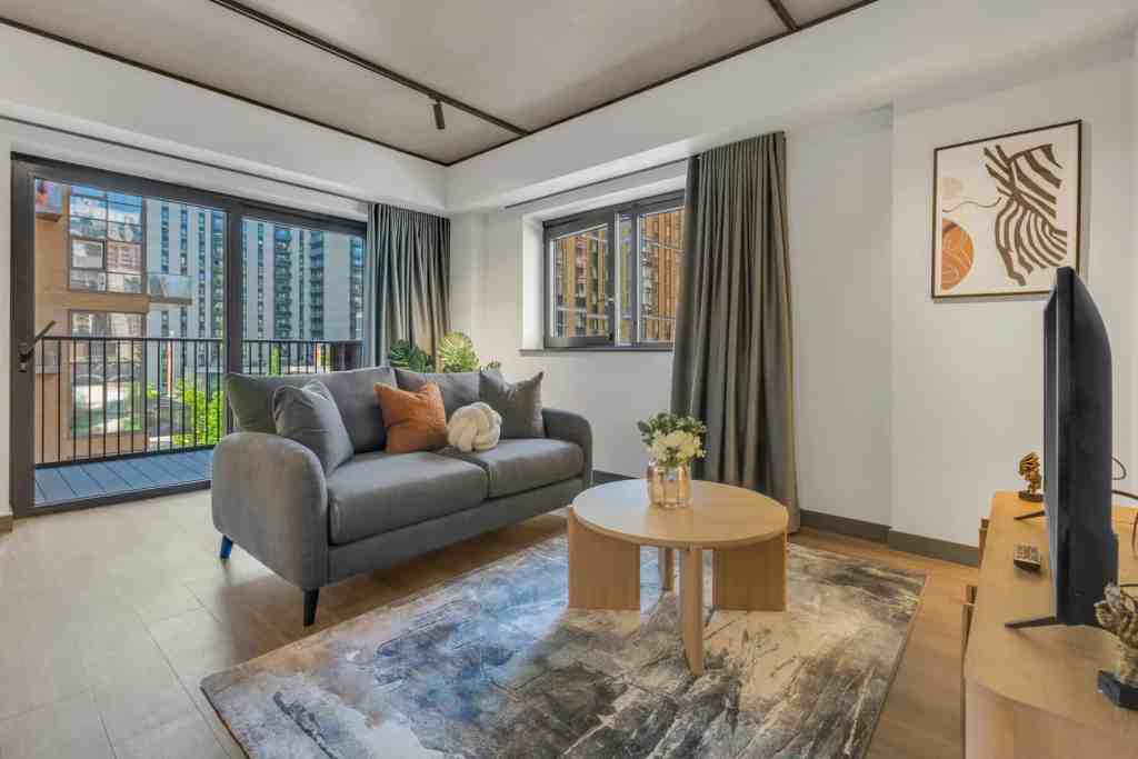Bright living room with large windows, city skyline, and contemporary furniture.
