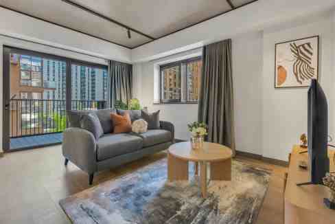 Bright living room with large windows, city skyline, and contemporary furniture.