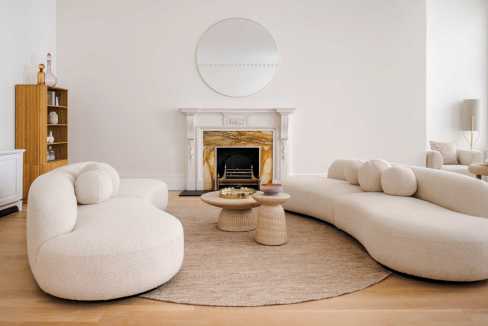 Elegant living room with plush white sofas and a marble fireplace, perfect for contemporary home dec.