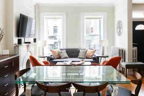 Bright living room with large windows, sofa, and dining table.
