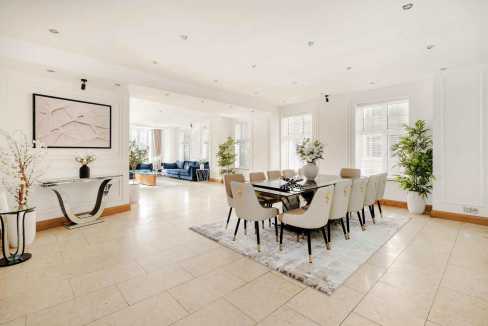 Spacious dining area featuring a sleek black table, white chairs, and contemporary artwork.