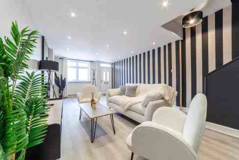 Modern living room with striped accent wall, comfortable sofa, and stylish decor.