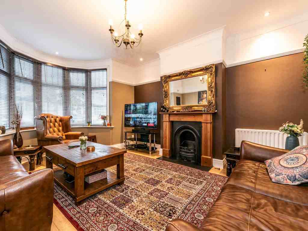 Charming living room with leather sofas, antique mirror, and a fireplace.