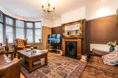 Charming living room with leather sofas, antique mirror, and a fireplace.