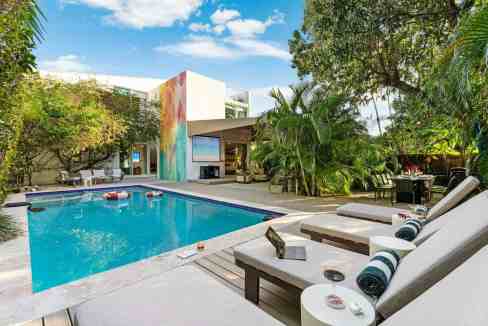 Outdoor swimming pool with sun loungers, tropical plants, and modern architecture in a luxurious set.