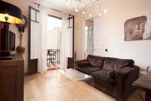 Bright living room with balcony doors, cozy sofa, and contemporary art piece.
