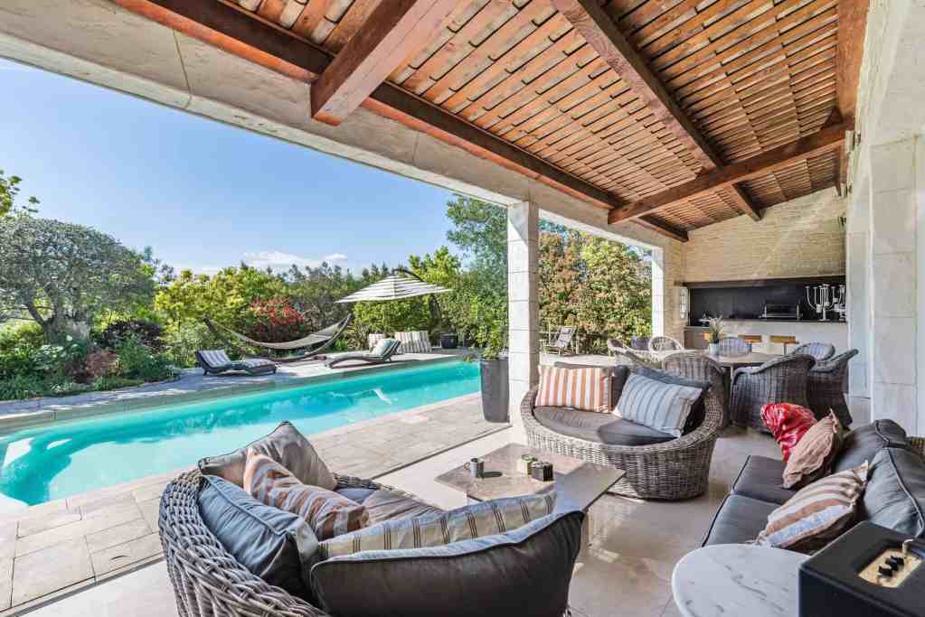 Outdoor lounge with pool, hammock, and lush garden view for relaxation and entertainment.