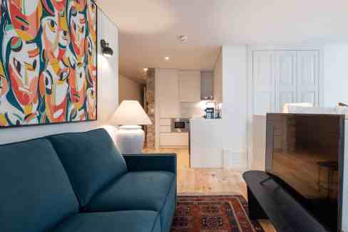 Modern living room with colorful abstract art, teal sofa, and contemporary decor.