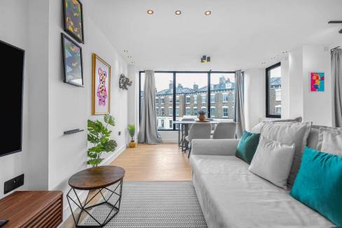 Bright modern living room with large windows, contemporary art, and cozy seating.
