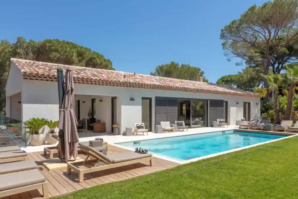 Luxury villa with swimming pool, outdoor lounge, and lush garden setting.