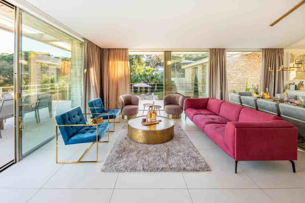 Bright contemporary living room with vibrant velvet sofas and expansive glass doors.