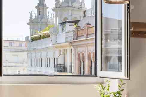 Cityscape view from a stylish apartment window with historic buildings and clear sky.