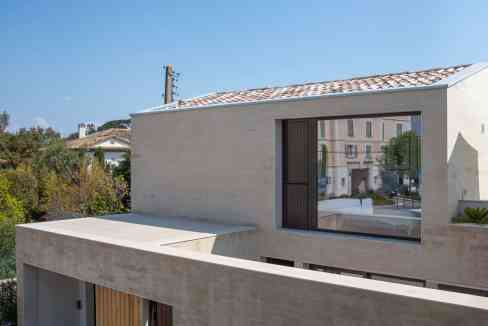 Contemporary minimalist house featuring beige stone walls, large windows, and a sleek architectural.