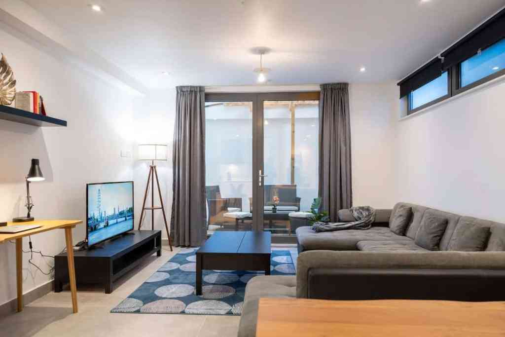 Living room with gray sofa, TV, and balcony in a contemporary apartment.