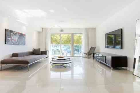 Bright modern living room with large windows, minimalist furniture, and a spacious open layout.