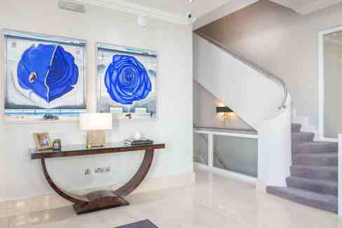 Modern interior with blue abstract paintings and staircase in a contemporary home.