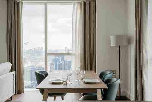 Contemporary dining room with city skyline view and minimalist design.