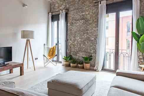 Bright living room with exposed brick wall, large windows, and stylish decor. Perfect for contempora.