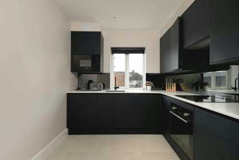 Black kitchen cabinets and appliances in a modern, minimalist kitchen design.