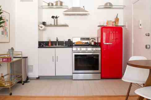 Modern kitchen with red retro refrigerator, white cabinets, and open shelving for a sleek, contempor.
