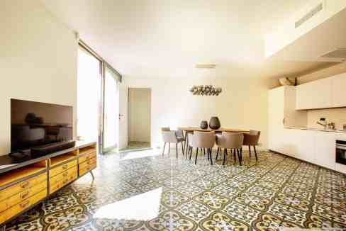 Bright and spacious open-plan living and dining room with stylish decor and patterned tile flooring.