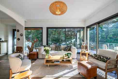 Bright living room with large windows showcasing lush outdoor scenery and natural light. Stylish fur.