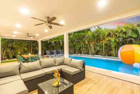 Outdoor living area with pool, tropical greenery, and cozy seating for relaxation.