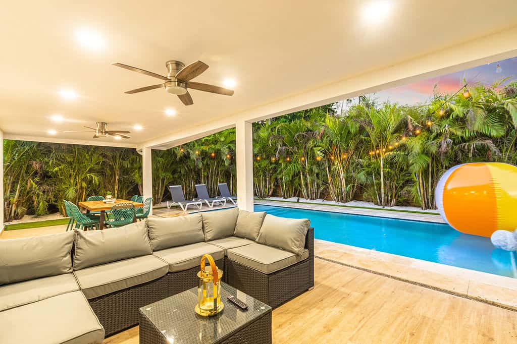 Outdoor living area with pool, tropical greenery, and cozy seating for relaxation.