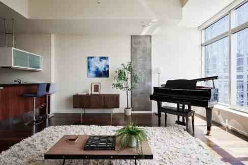 Spacious living room featuring a grand piano, contemporary decor, and large windows with city views.