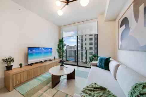 Bright living room with balcony, cityscape view, modern decor, and natural light.