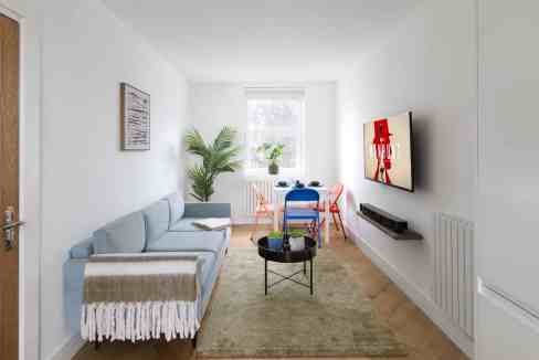 Modern minimalist living room with a wall-mounted TV, cozy sofa, and large window providing natural.