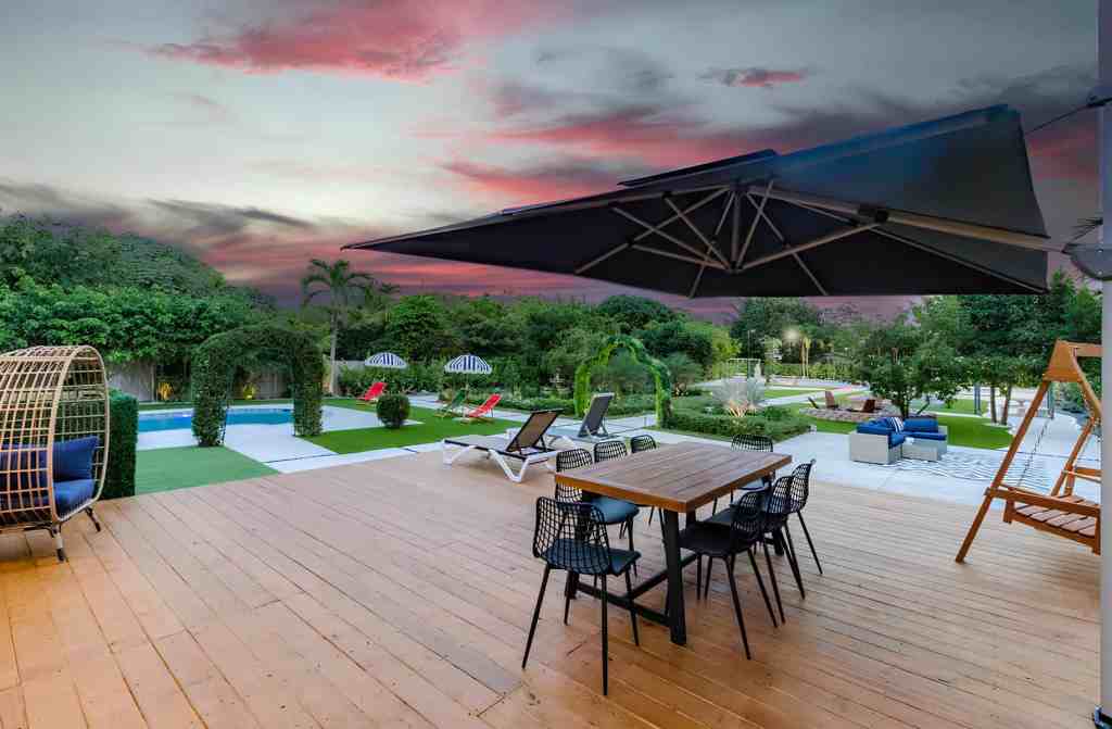 Scenic outdoor patio with lounge chairs, dining table, and umbrellas at sunset.