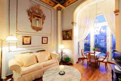 Cozy living room featuring vintage furniture, ornate wall decor, and a bright window overlooking a c.