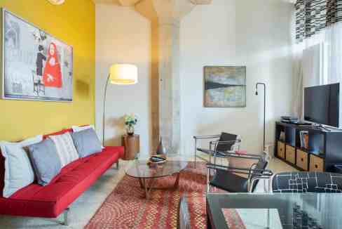 Bright living room featuring a red sofa, abstract art, and contemporary furniture.