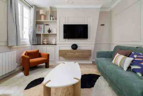 Contemporary living room with sofa, armchair, and wall-mounted TV.