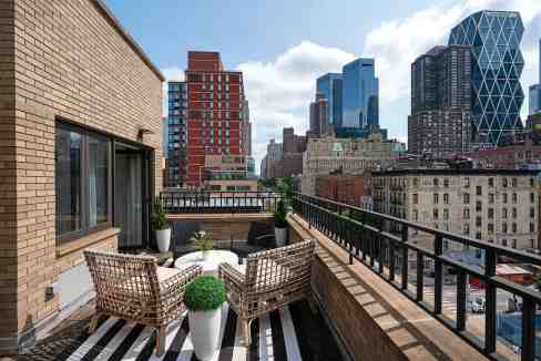 Rooftop terrace overlooking NYC skyline with outdoor furniture and urban architecture.