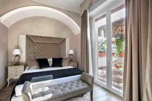 Cozy bedroom with balcony, elegant decor, and natural light.